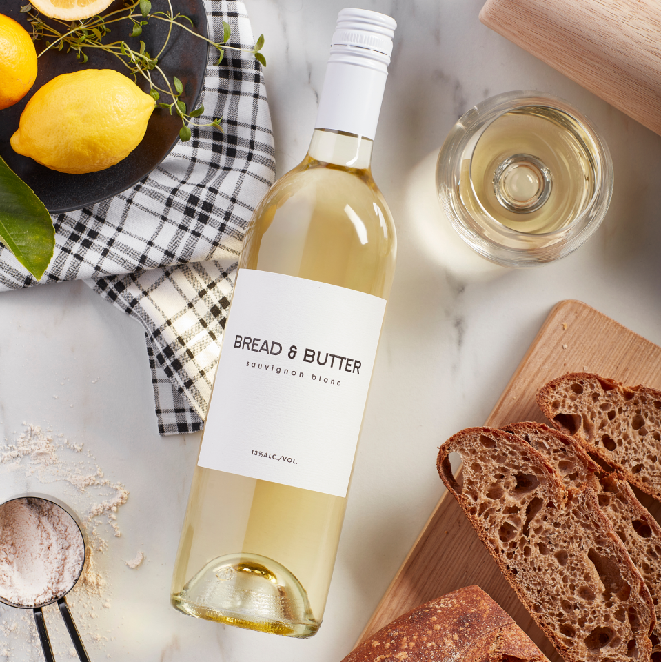 Bread & Butter Sauvignon Blanc on a table with bread, lemons, flour and a glass of wine poured.