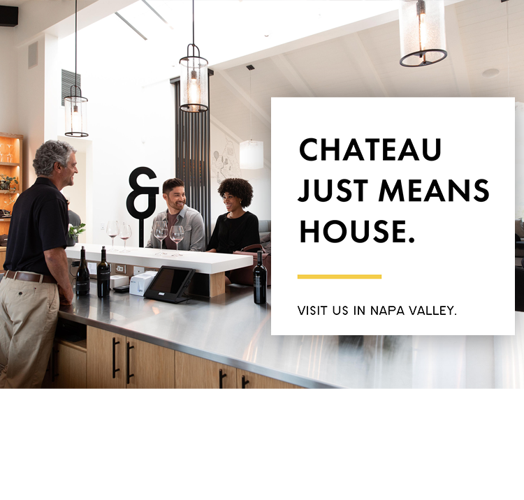 Interior of the Bread & Butter Wines Tasting Room in Napa with a host serving guests wine at the tasting room. Includes copy overlaid that said, "Chateau Just Means House. Visit us in Napa Valley."