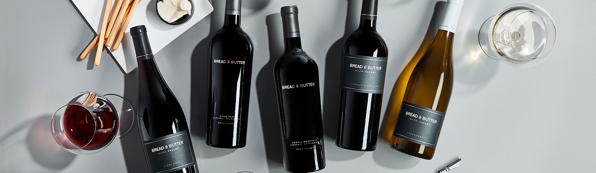 Bread & Butter Shop All Wines Header Image featuring Napa Valley and Cellar Collection Wines. From left to right: Napa Valley Pinot Noir, Atlas Peak Cabernet Sauvignon, Howell Mountain Cabernet Sauvignon, Napa Valley Cabernet Sauvignon, and Napa Valley Chardonnay.