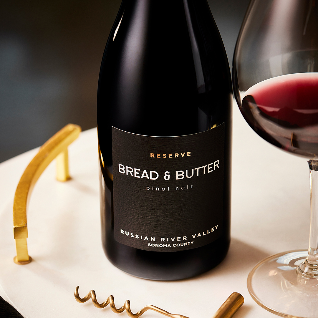 Bread & Butter Reserve Russian River Valley Pinot Noir on a marble tray with gold handles next to a wine glass and gold wine key