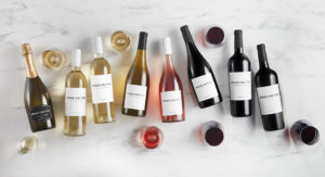 Bread & Butter Everyday Wines on a marble table. From left to right: DOC Prosecco, Sauvignon Blanc, Pinot Grigio, Chardonnay, Rose, Pinot Noir, Cabernet Sauvignon, Merlot.