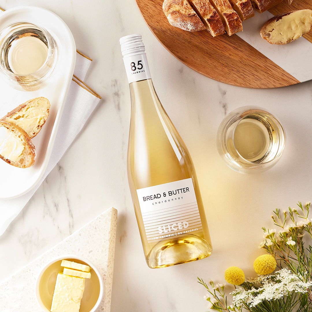 Bread & Butter's Low-Calorie, Low Alcohol, "Sliced" Chardonnay on a marble table with bread, butter and florals.